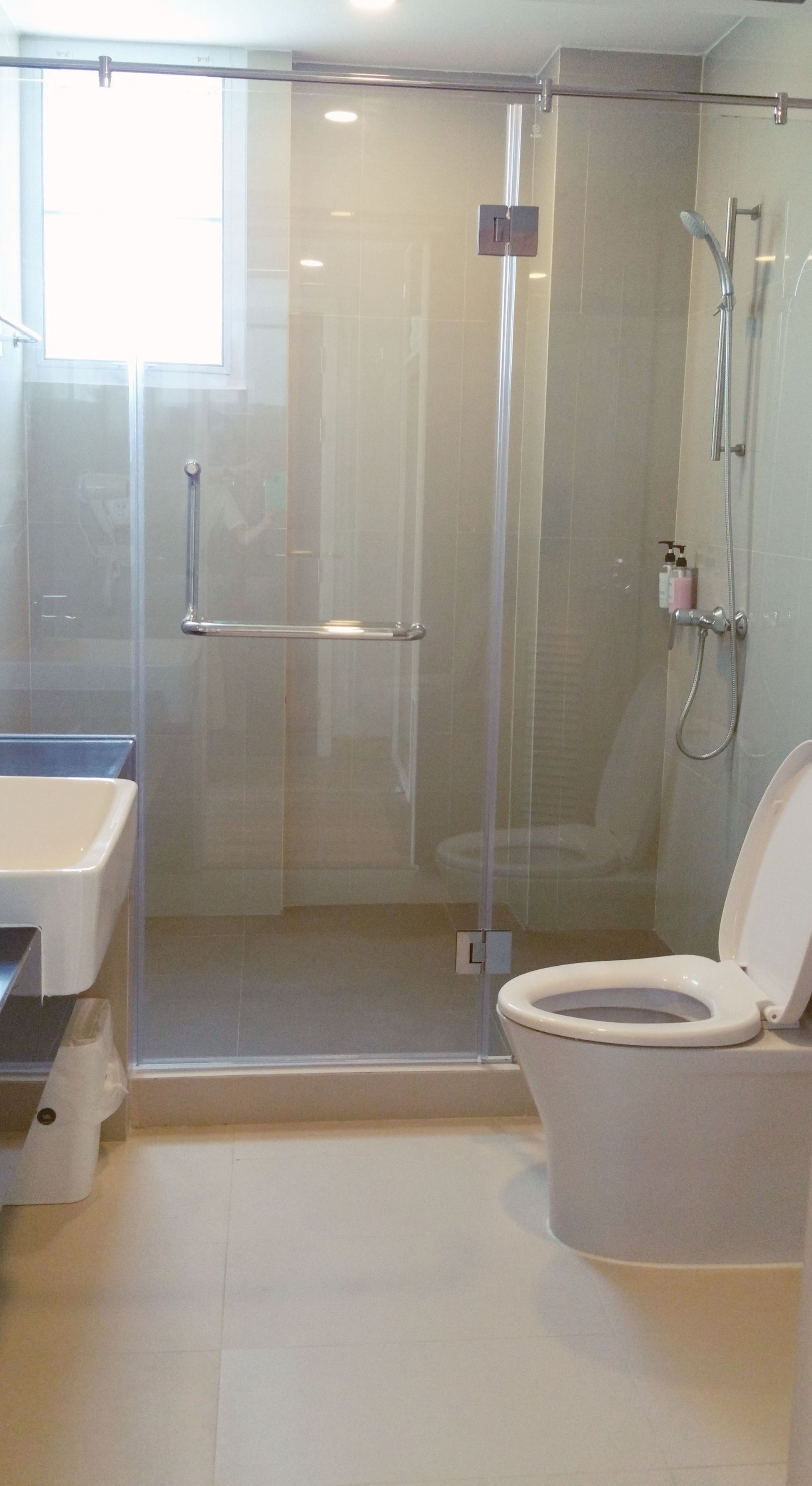 A modern bathroom with a glass-enclosed shower, a toilet, and a sink.