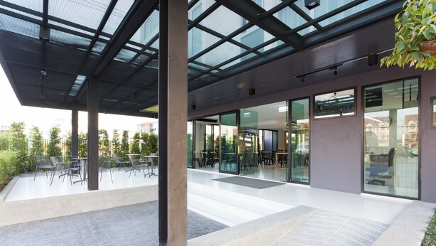 Un vestíbulo de hotel moderno con puertas de vidrio, un área de descanso con mesas y sillas, y vistas a la ciudad.
