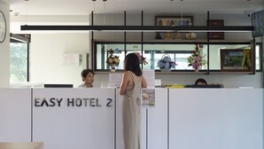 Una recepción en Easy Hotel 2 con un diseño moderno, un reloj y una ventana con flores.