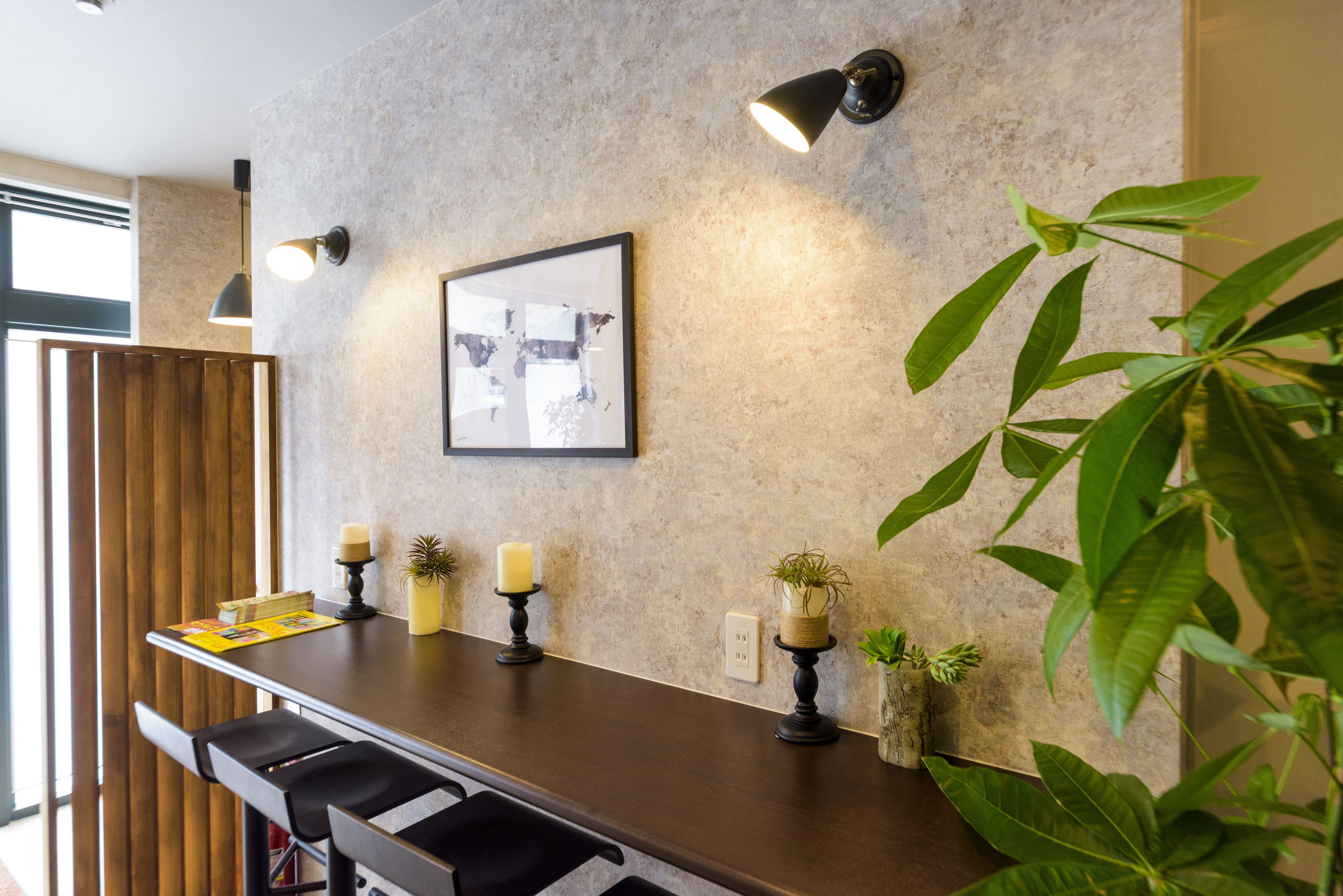 A modern kitchen with a dark countertop, pendant lighting, and a framed picture on the wall.