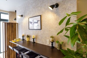 Eine moderne Küche mit dunkler Arbeitsplatte, Pendelleuchten und einem gerahmten Bild an der Wand.