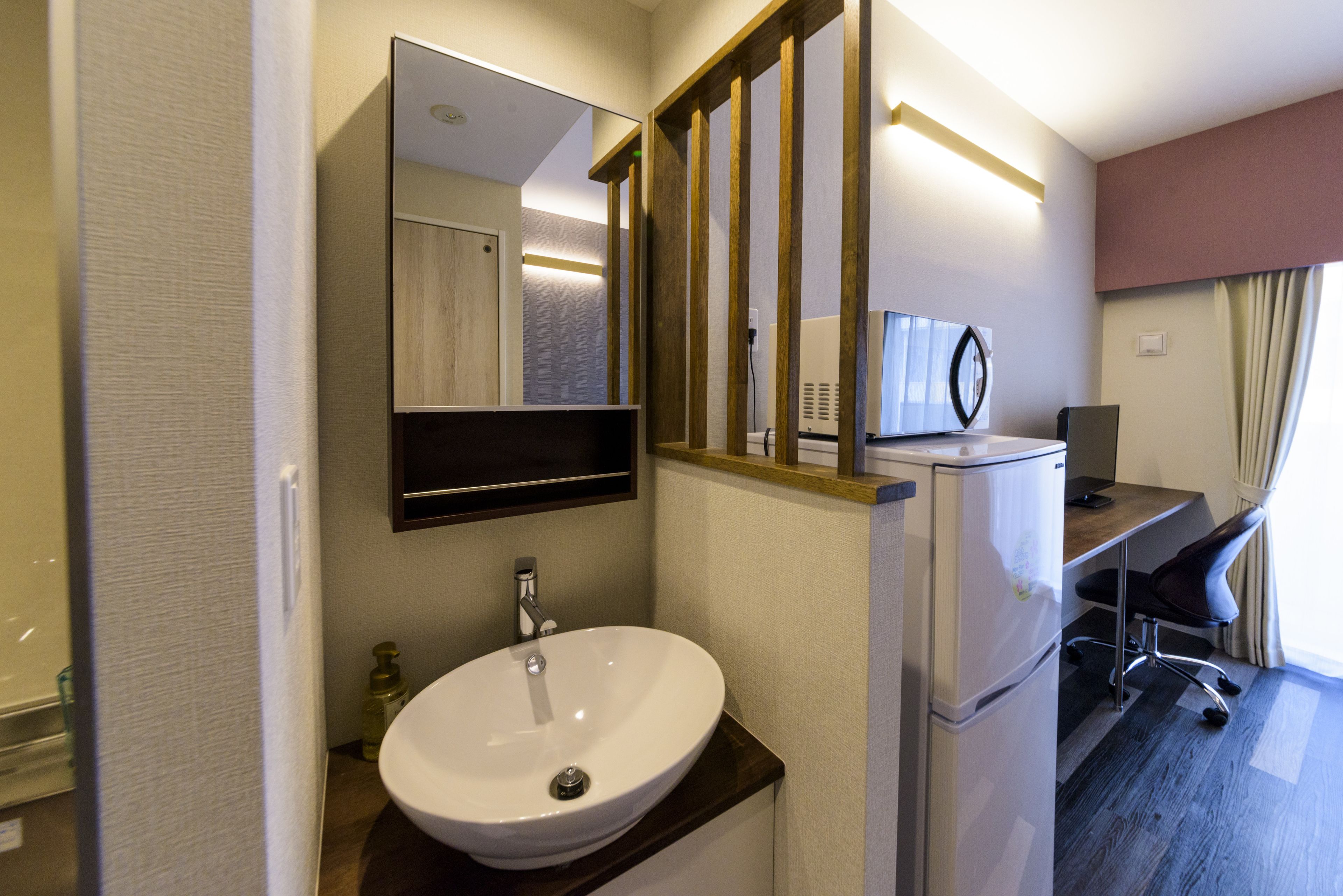 A modern bathroom with a white sink, a mirror, and a wooden-framed window.