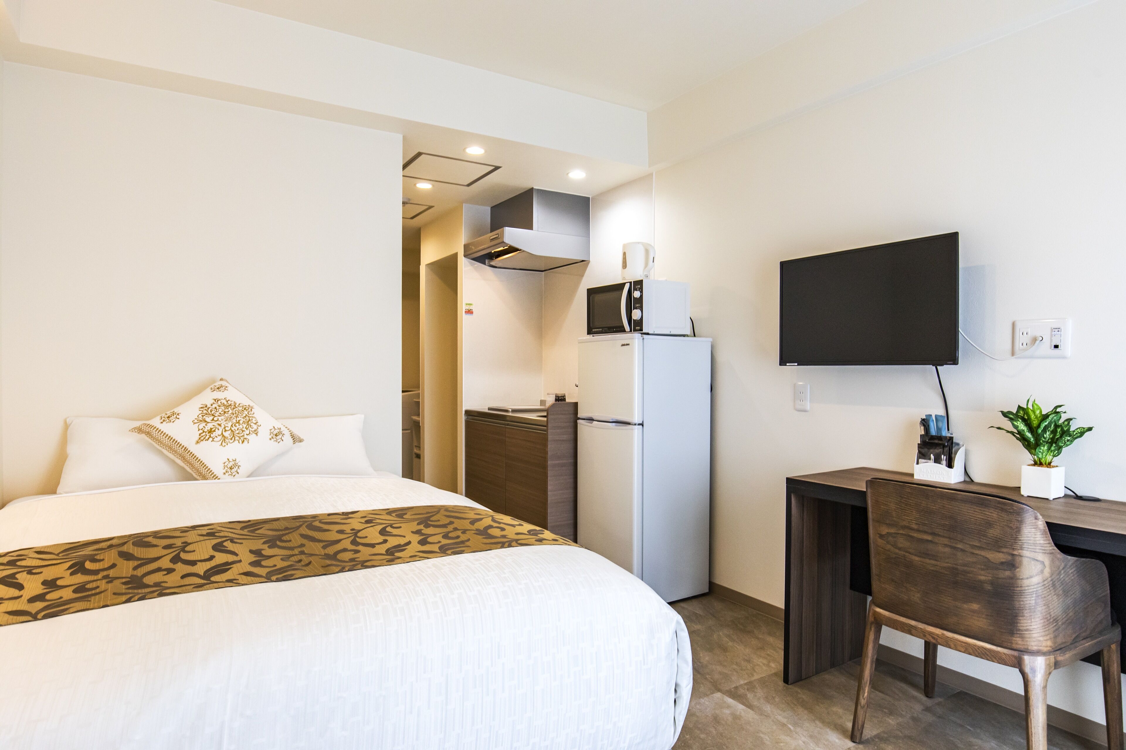 A hotel room with a bed, a desk, a television, a refrigerator, and a microwave.