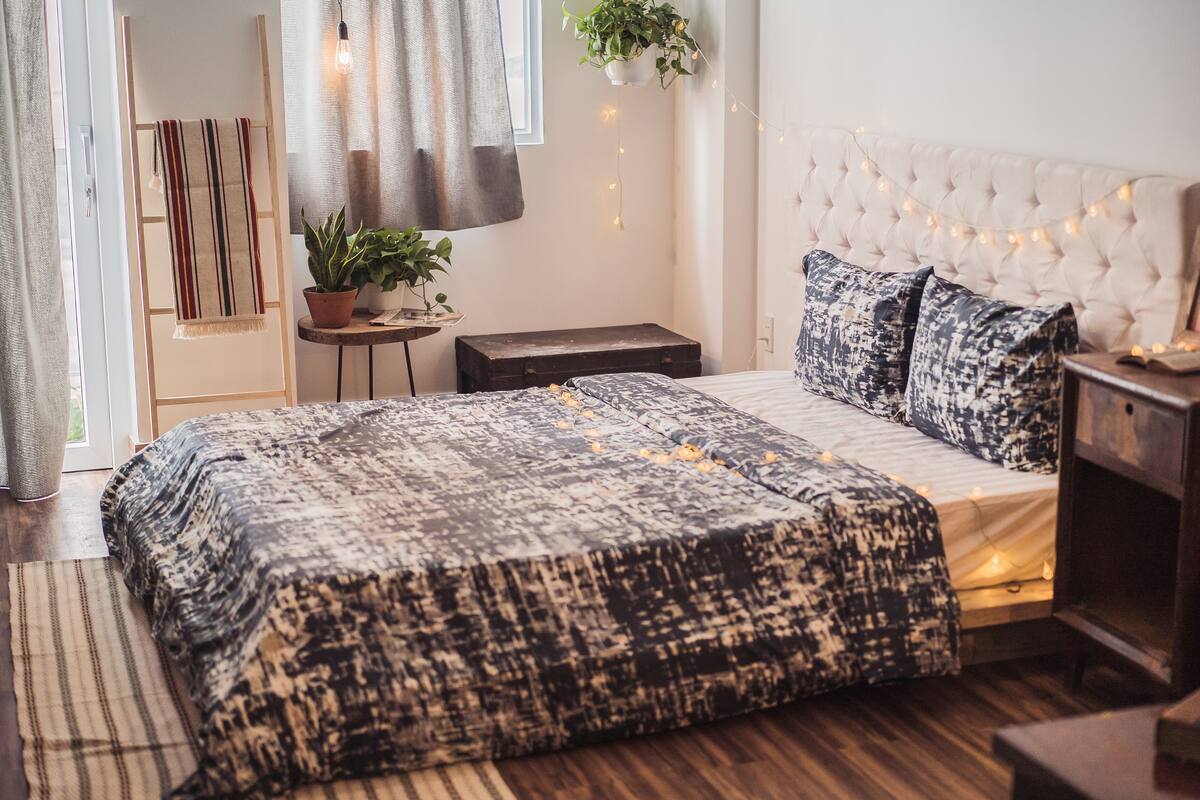 Une chambre à coucher avec un lit, une table de chevet et une plante suspendue.