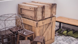 Eine rustikale Holzbank mit einem Drahtkorb, gestapelten Holzkisten und einem Fliesenboden.