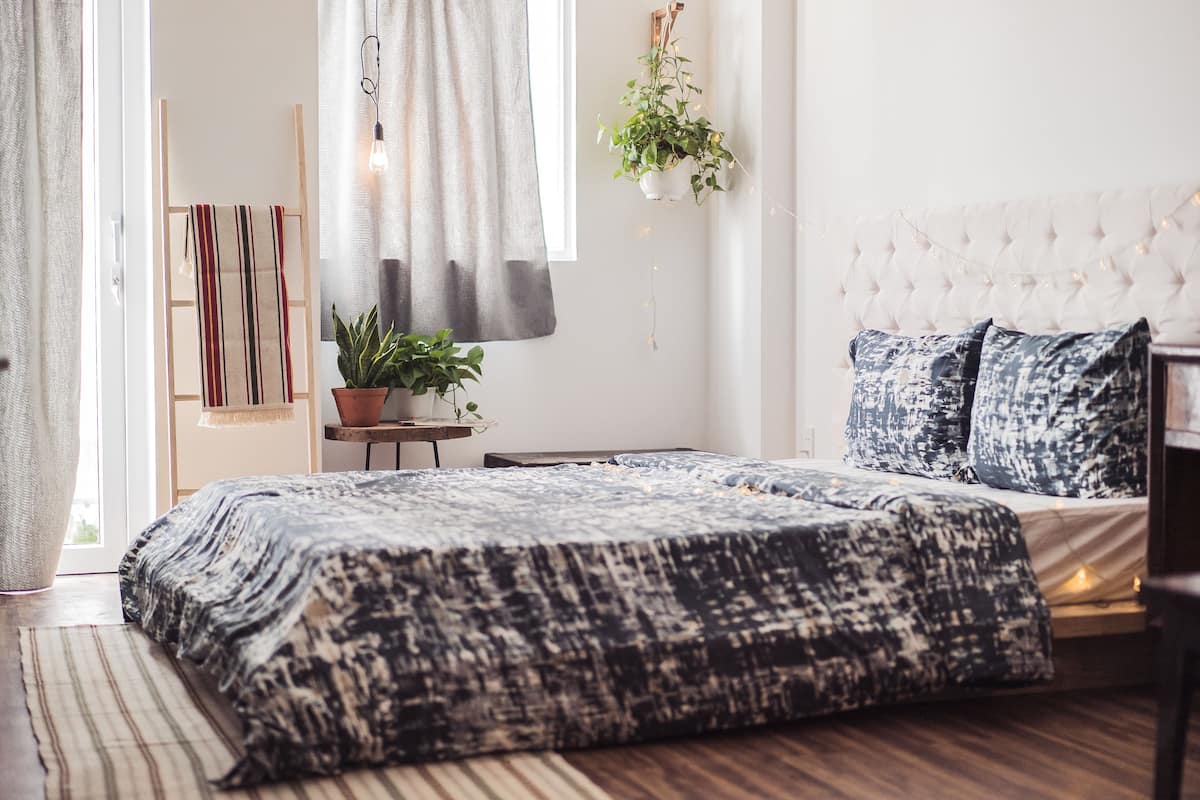 Une chambre à coucher avec un lit, une table de chevet et une plante suspendue.