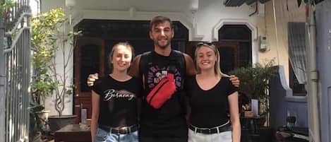 Tres personas de pie frente a un edificio con un letrero que dice "Shark Homestay".