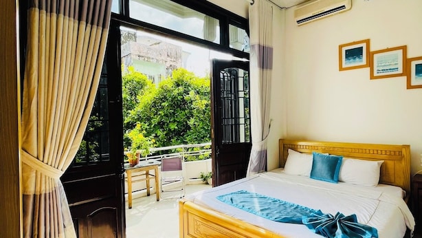 A bedroom with a wooden bed, a view of greenery outside, and a ceiling with a patterned design. - Shark Hotel - Hostel (Hue)