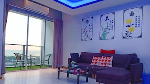 A living room with a sofa, a coffee table, and a view of the outdoors through a glass door. - Sekinchan Seaview Homestay (Sekinchan)