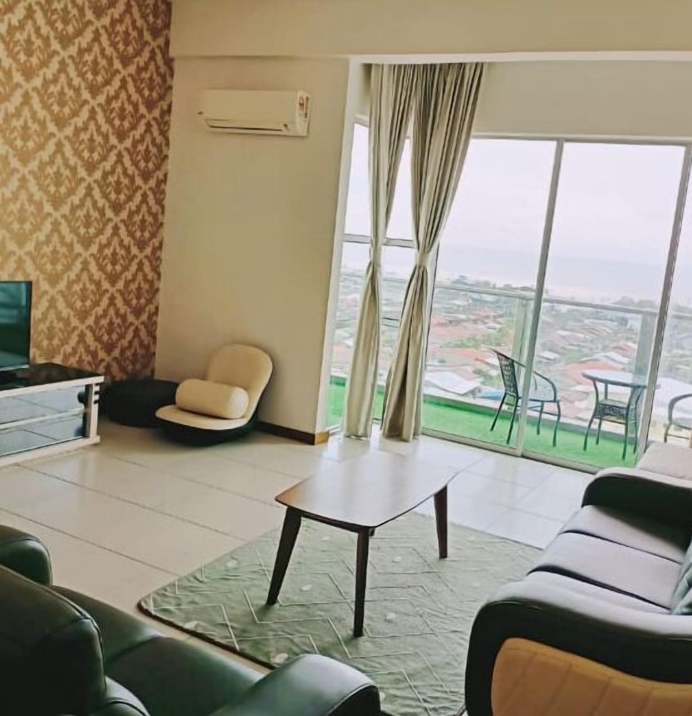 Ein modernes Wohnzimmer mit einer Couch, einem kleinen Tisch und einem Sessel. Ein großes Fenster mit Vorhängen bietet Blick auf die Stadt.