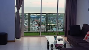 A modern living room with a large sliding glass door leading to a balcony with a city view. - Sekinchan Seaview Homestay (Sekinchan)