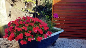 Un grand bac à fleurs orné de fleurs rouges, posé sur du gravier.