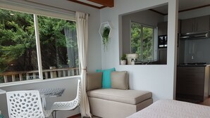 Une chambre avec un grand lit, une fenêtre avec des rideaux, un canapé avec des coussins, une chaise et une petite table.