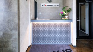 A reception area with a tiled wall, a welcome sign, and a doormat with the hotel name. - Mr.KINJO in ISHIKAWA inter (Uruma)