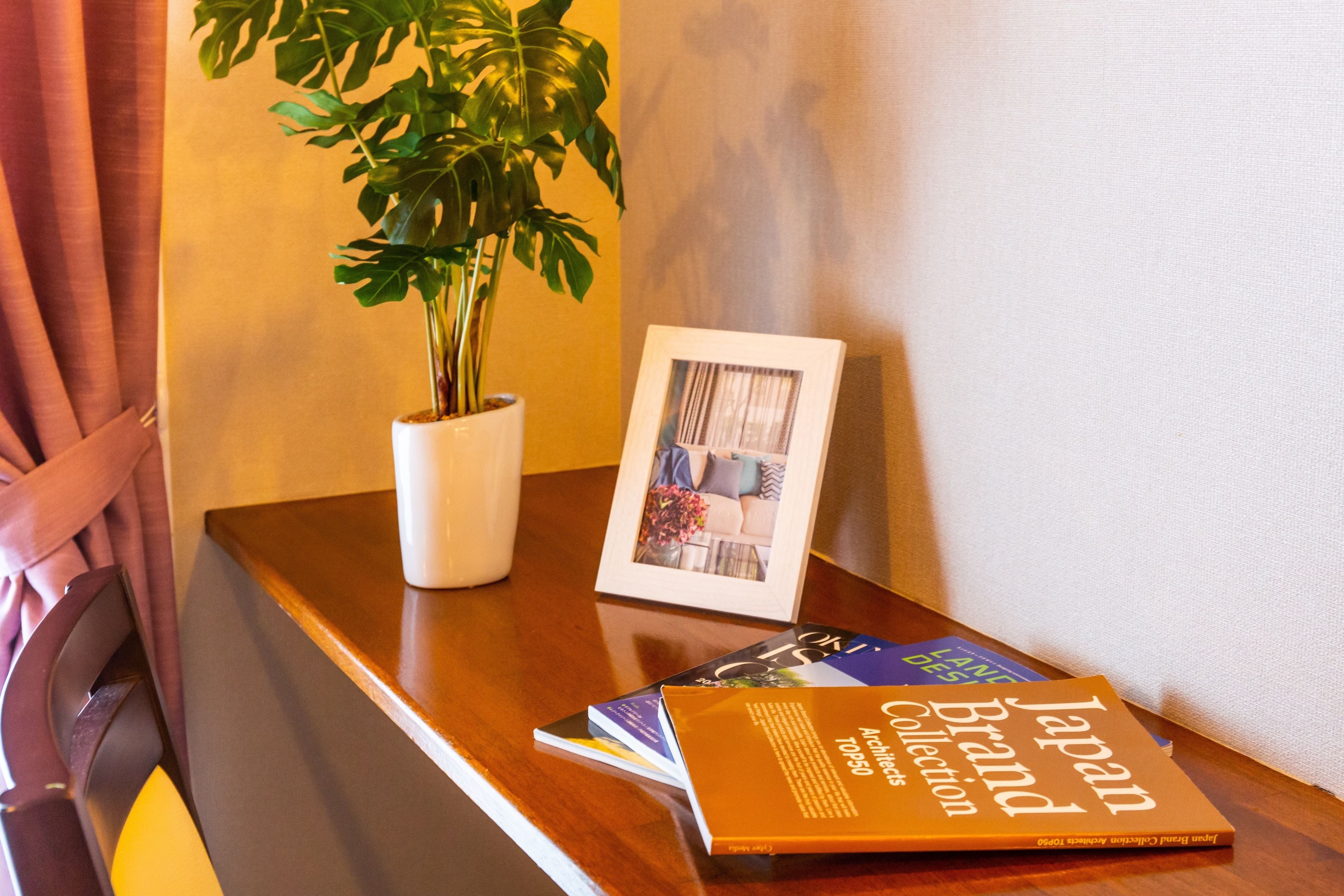A wooden table with a potted plant, a framed photograph, and a book titled "Japan Brand Collection".