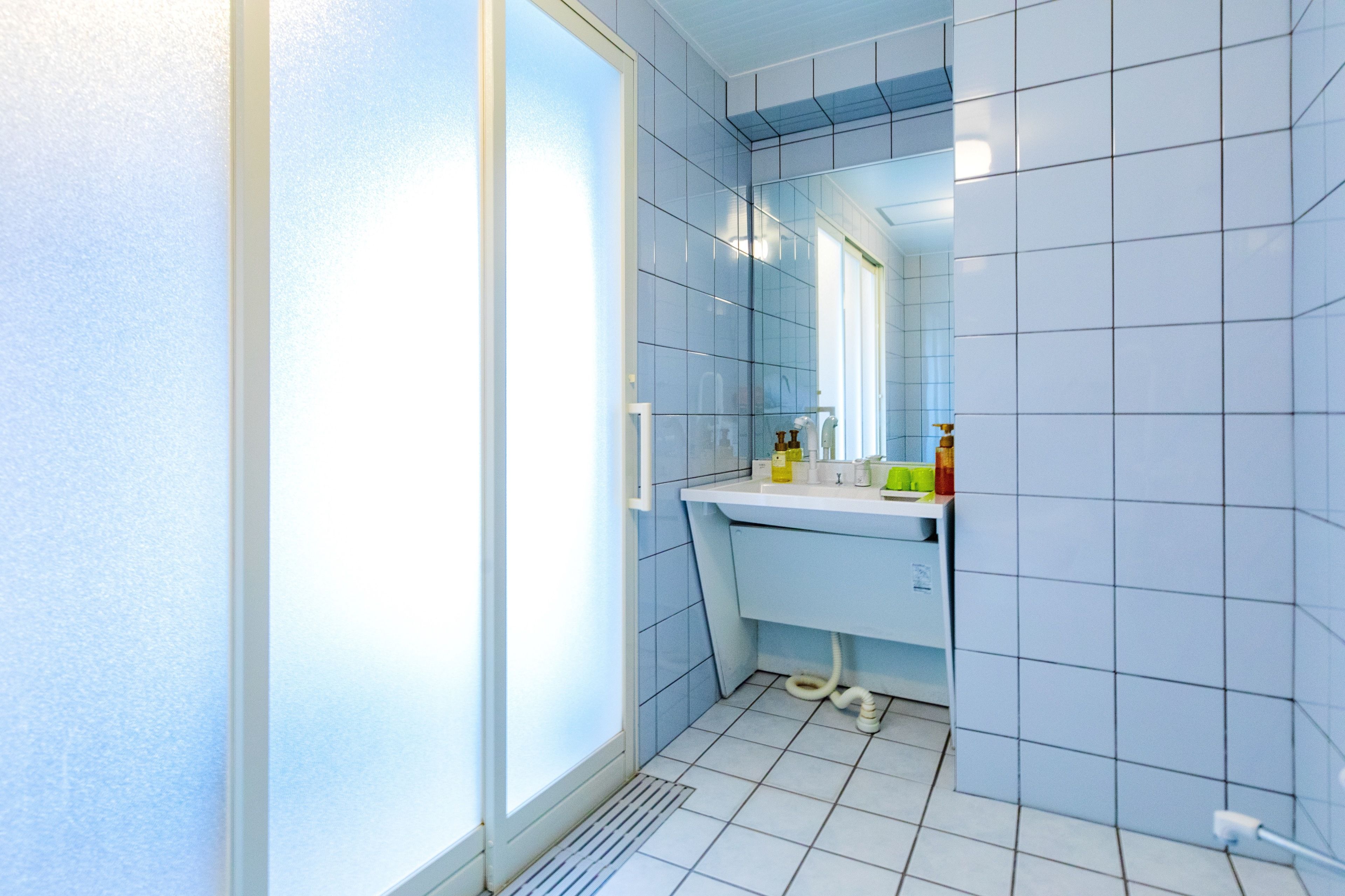 A bathroom with a white sink, mirror, and tiled walls.