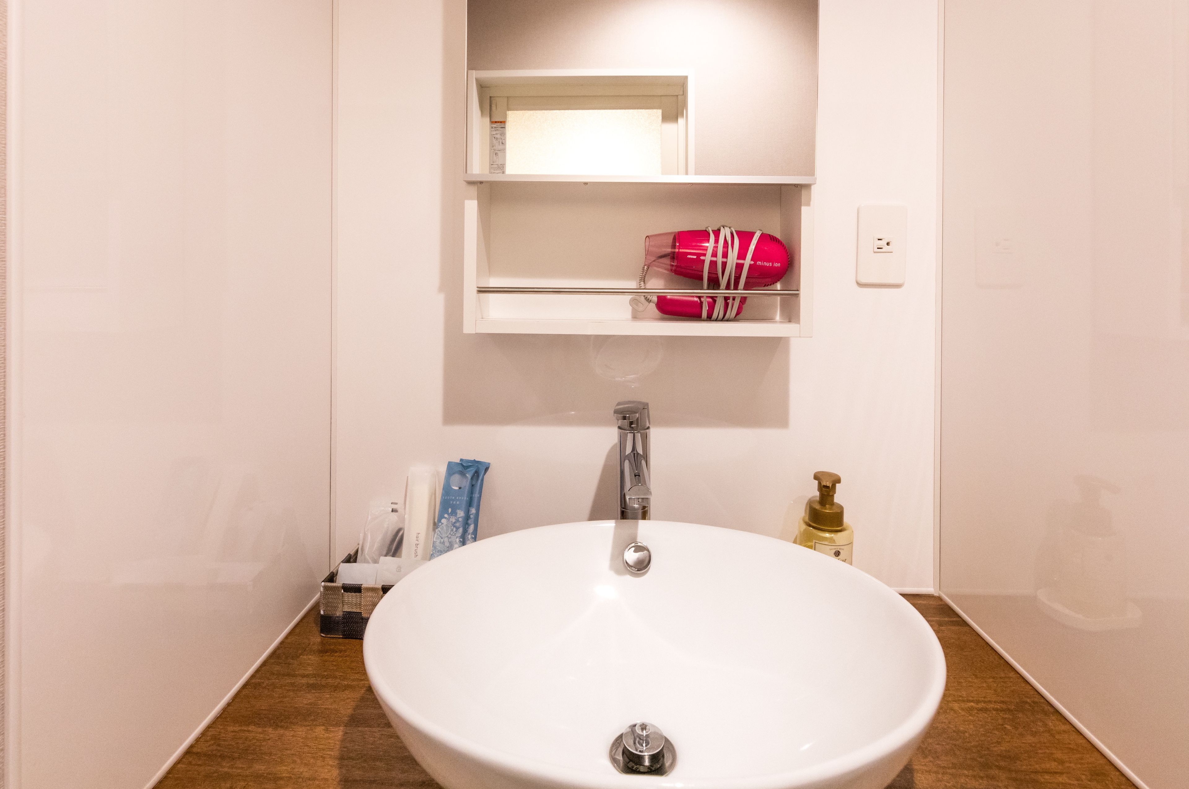 Ein Badezimmer mit einem weißen Waschbecken, einem Spiegel und einer Ablage für Pflegeprodukte.