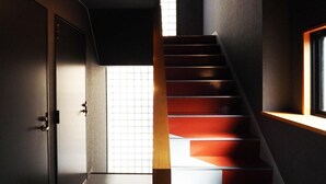 Una escalera moderna con barandilla de madera y vistas a una habitación con un ventanal grande.