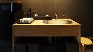 Un baño moderno con un tocador de madera, un lavamanos y un microondas.