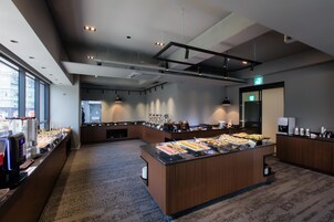 A modern breakfast bar with a variety of food options, a coffee machine, and a seating area with a view of the city.