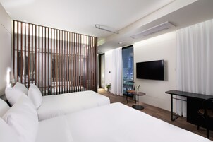 A modern hotel room with a large bed, a desk, a chair, and a TV mounted on the wall.