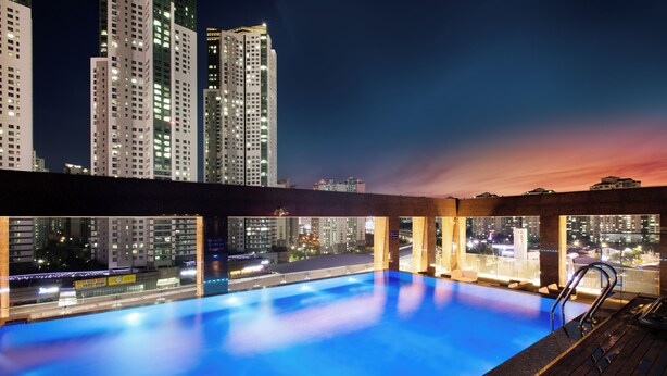 Una piscina en la azotea con vista a la ciudad al atardecer.