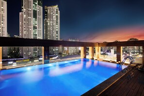 Una piscina en la azotea con vista a la ciudad al atardecer.
