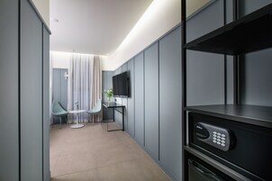 A modern hotel room with a flat-screen TV, a small table with two chairs, and a minibar.