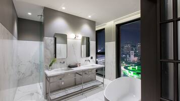 Un baño moderno con una bañera grande, lavamanos dobles y cabina de ducha con mampara de vidrio.