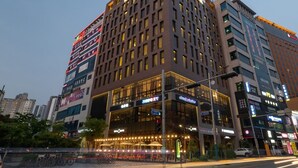 Un hotel moderno con un llamativo letrero que dice 'Park Inn Hotel', varios pisos y una fachada bien iluminada.