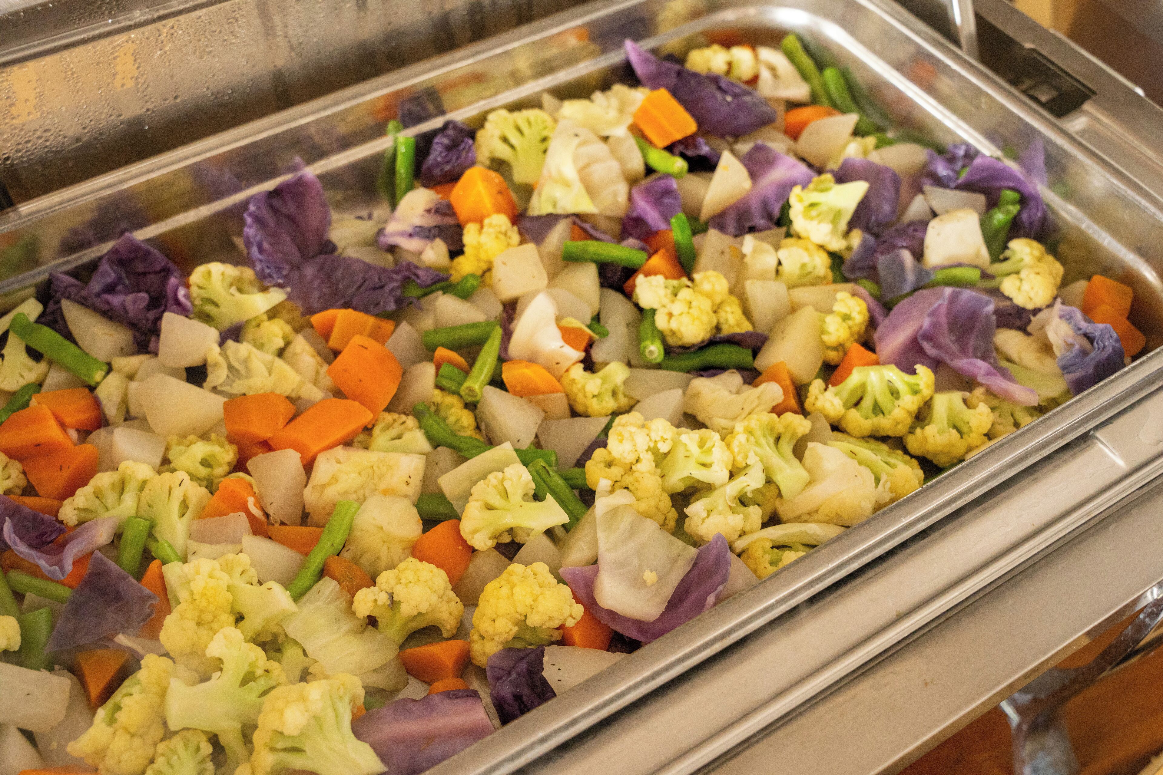 A buffet with a variety of vegetables including cauliflower, carrots, and green beans.