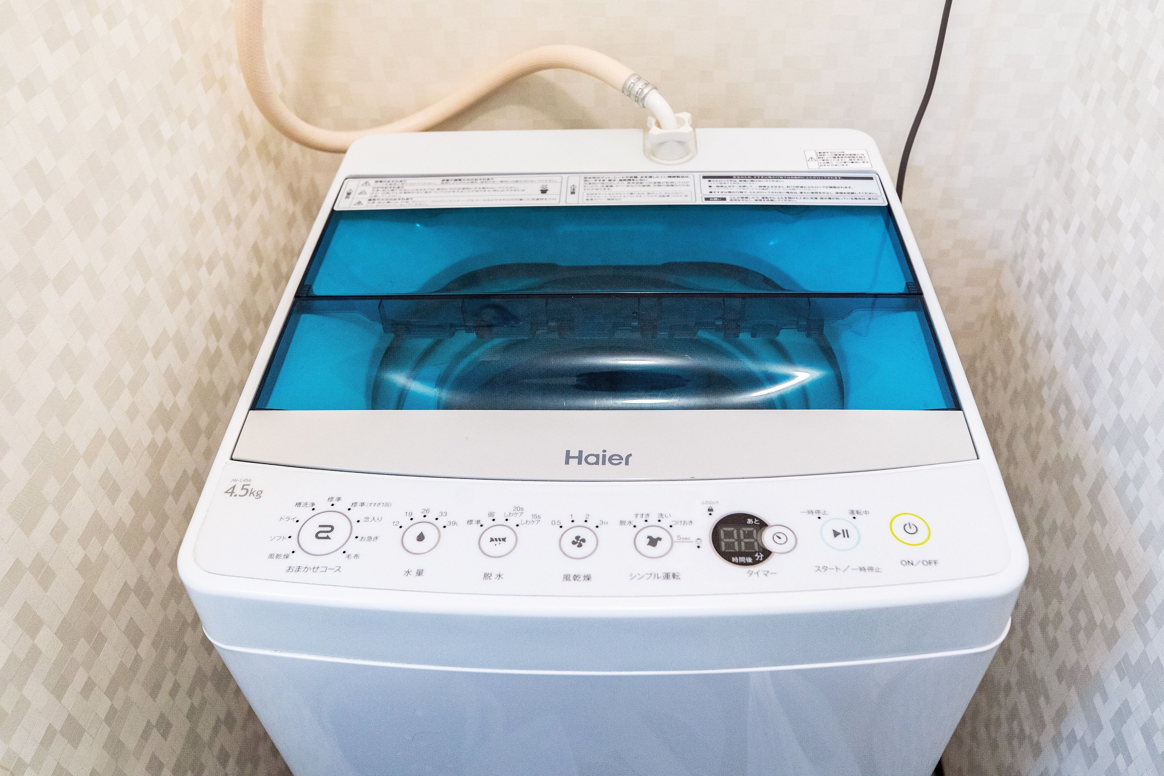 A white Haier washing machine with a transparent water tank, control panel, and a power cord.