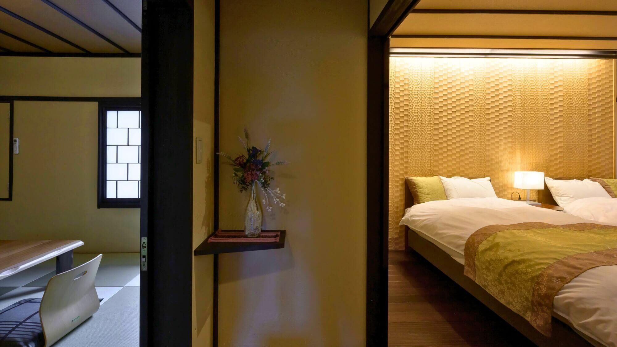Une chambre d’hôtel avec un lit, une table de chevet et un vase rempli de fleurs.