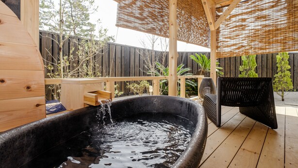 A wooden deck with a hot tub, outdoor furniture, and a bamboo screen. - Asahiya (Himi)