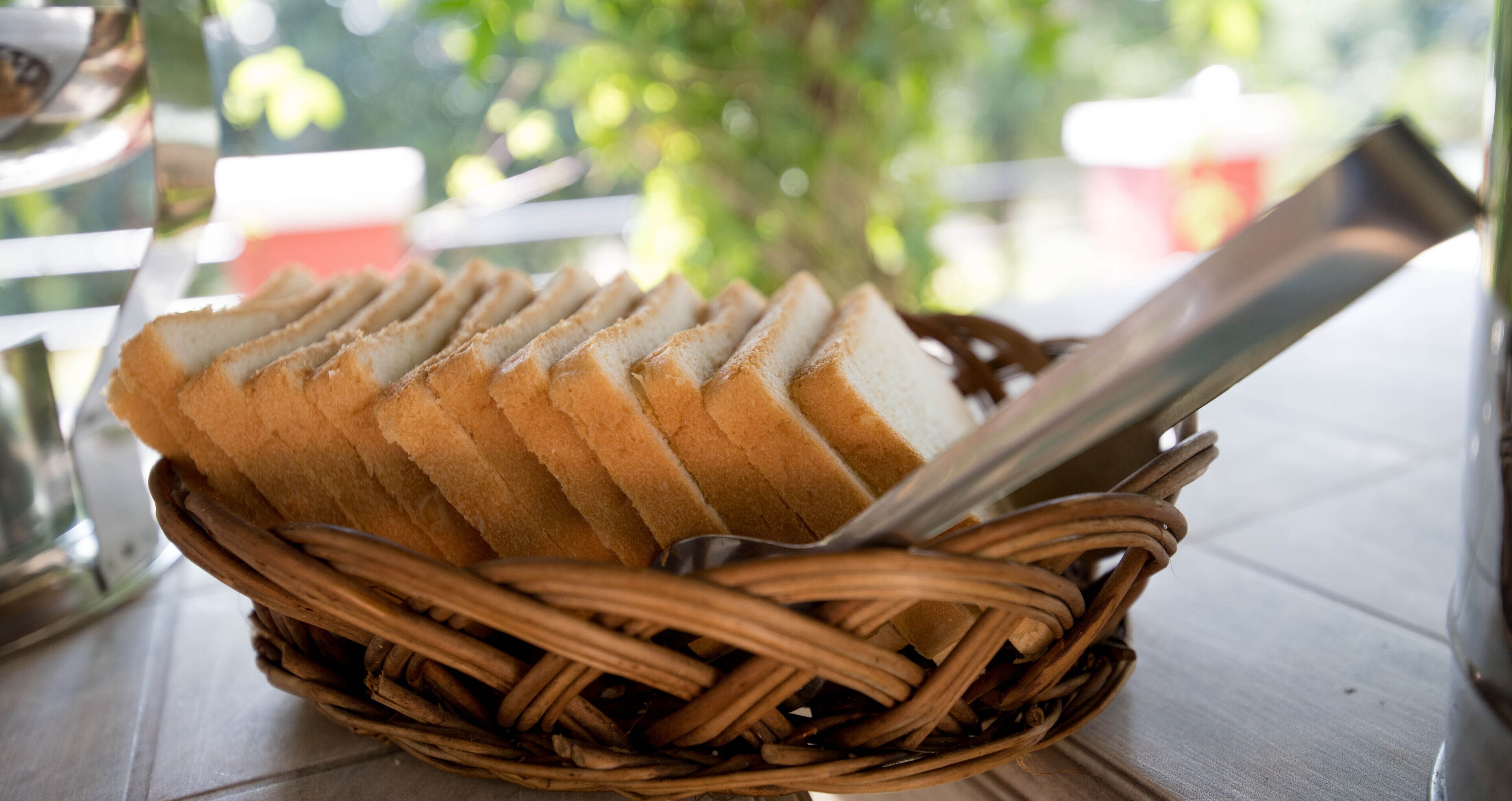 A basket of sliced bread on a table with a metal utensil.