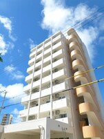 Un edificio de varios pisos con balcones, unidades de aire acondicionado y líneas eléctricas visibles.