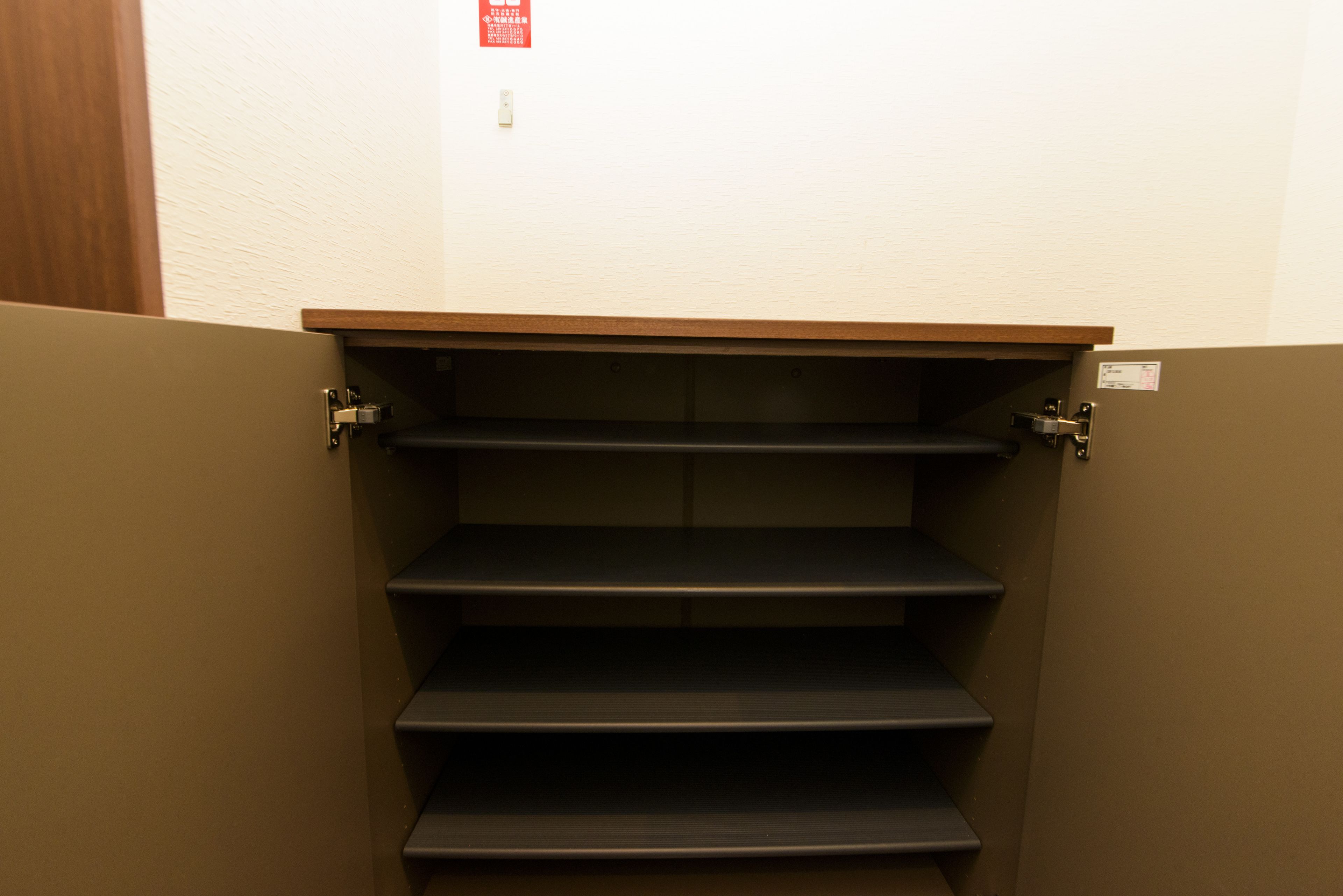 A set of dark-colored, empty steps leading to a higher floor, with a wooden ledge above and a red sign on the wall.