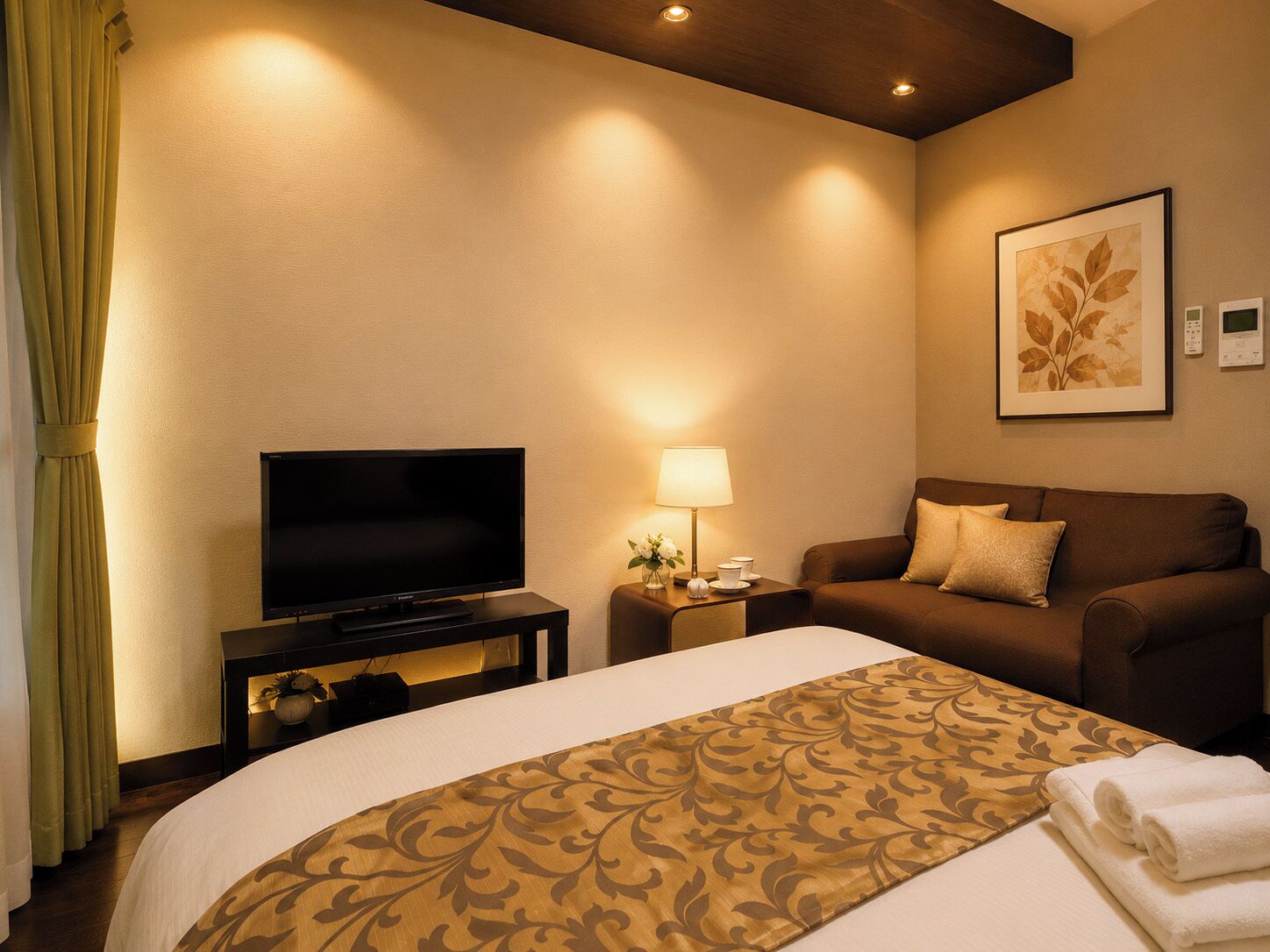 Habitación de hotel con cama, televisión, sofá, lámpara y un cuadro en la pared.