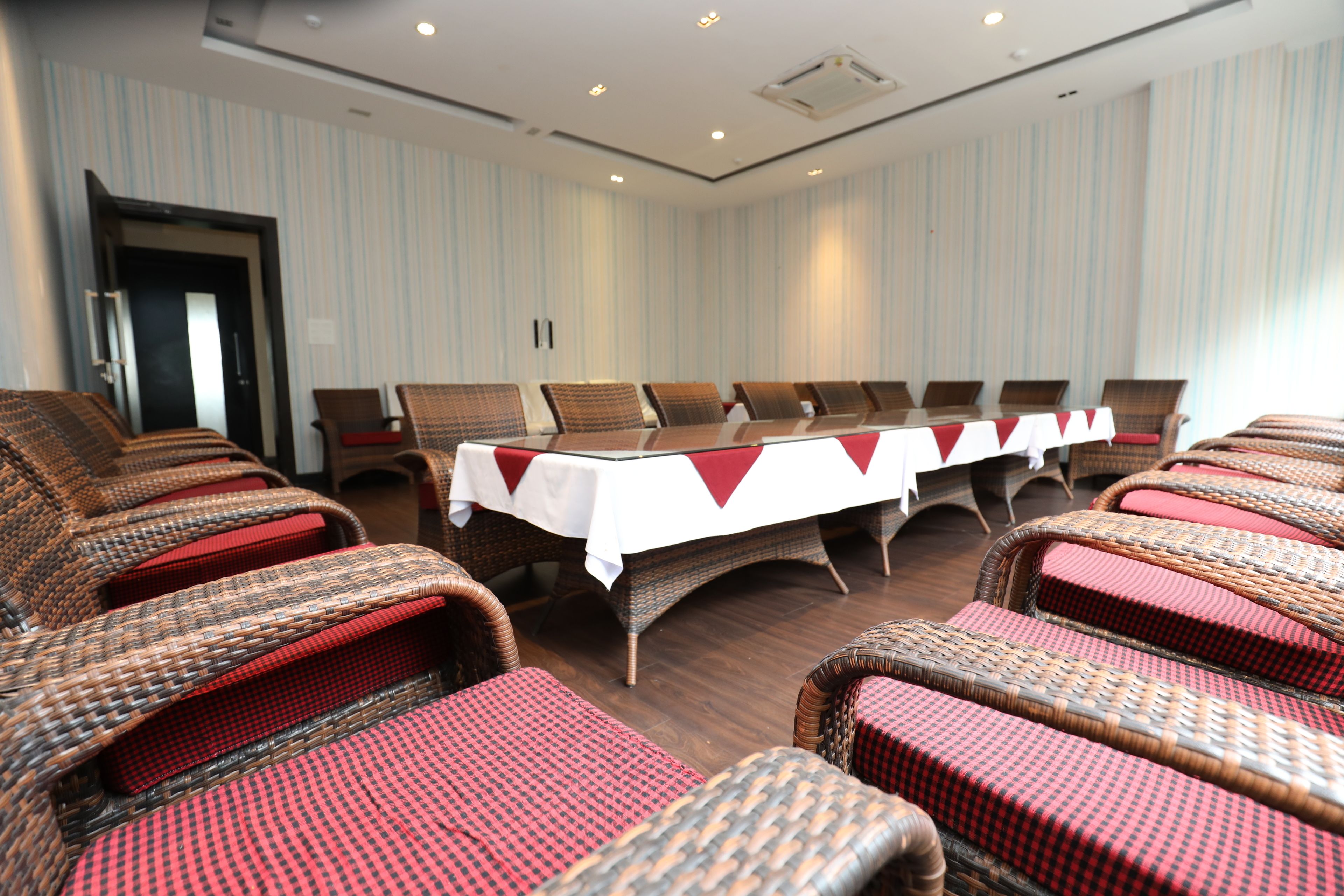 Un salón de conferencias con una larga mesa y sillas de mimbre.