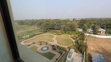 A view of a landscaped garden with a pool, pathways, and surrounding greenery.