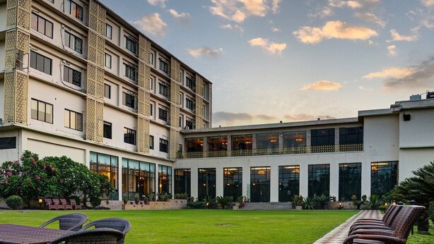 A multi-story hotel with a courtyard, outdoor seating, and a modern architectural design.