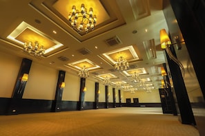 Un vestíbulo de hotel con múltiples candelabros, luces empotradas en el techo y piso alfombrado.