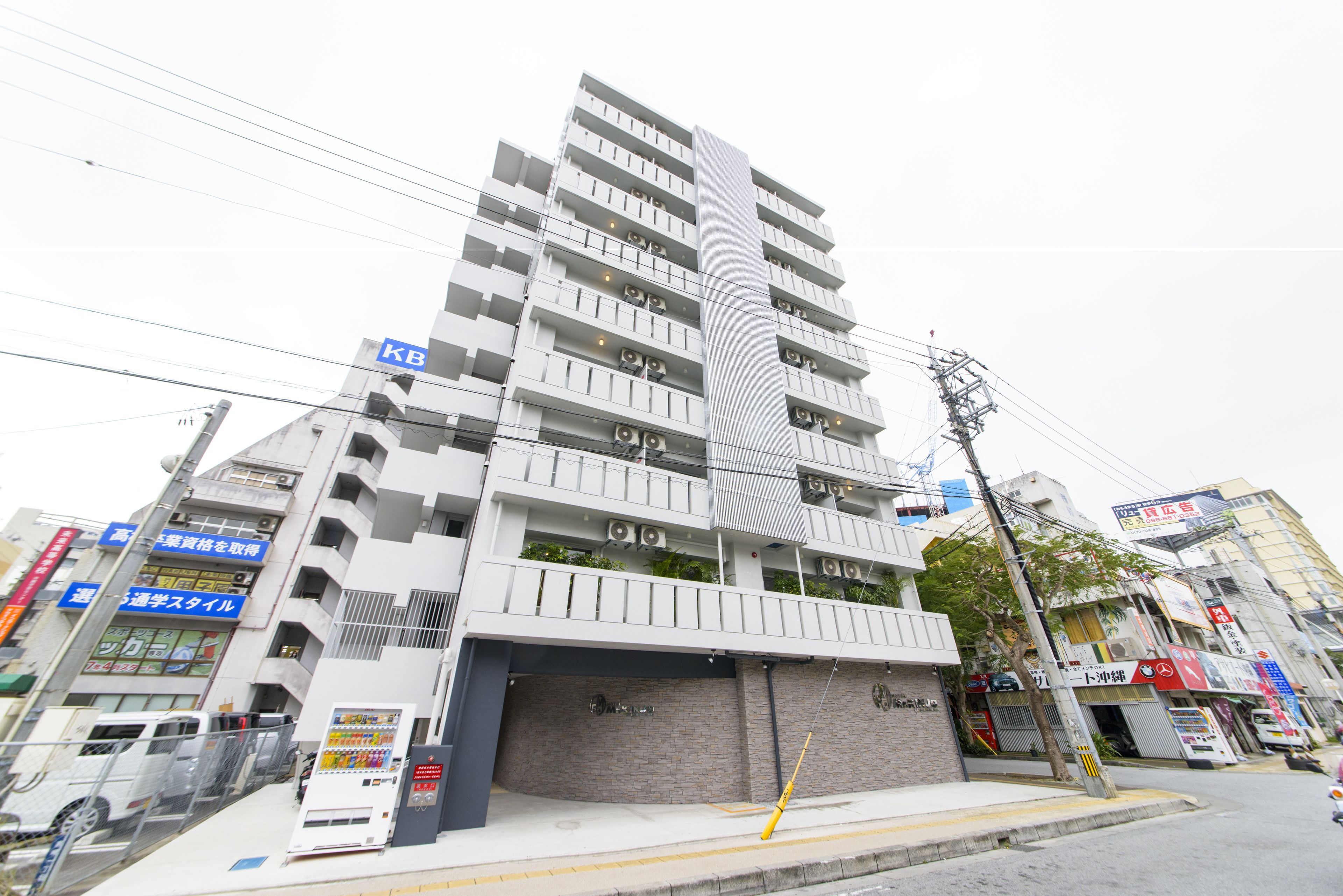 A multi-story building with a modern design, featuring balconies and air conditioning units.