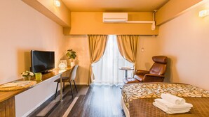 A hotel room with a bed, a desk with a TV, a chair, and a small table. - Mr.KINJO in Asahibashi station square (Naha)