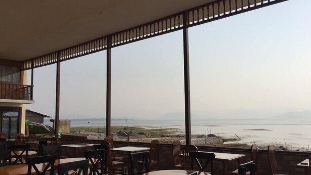 A restaurant with large windows offering a view of the sea and distant mountains.