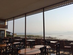A restaurant with large windows offering a view of the sea and distant mountains. - Pekon Princess Resort (Pekon)