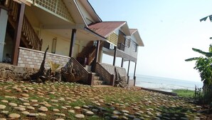 A beachfront property with a stone pathway leading to a wooden staircase, a balcony, and a view of the sea.