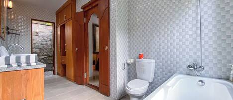A bathroom with a white bathtub, a toilet, and a sink with a soap dispenser.