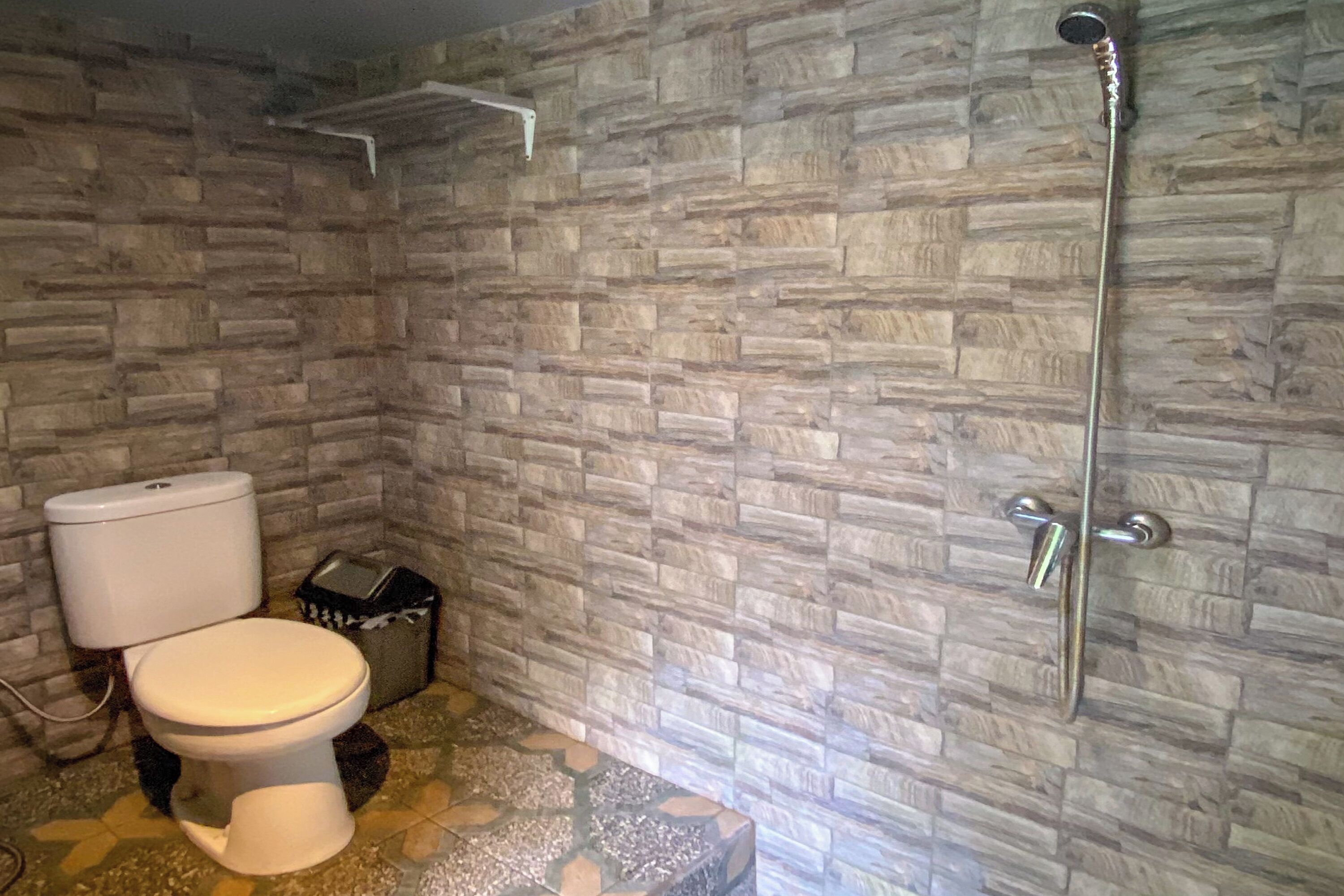 Un bagno con il water, una doccia e un pavimento piastrellato.