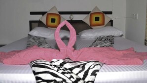 Habitación de hotel con una cama que destaca por un diseño original del cabecero, una toalla rosa y ropa de cama a rayas.